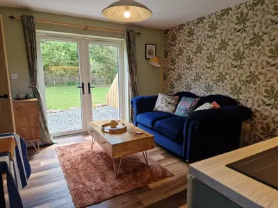 a living room with a blue couch and a table at The Drey by Blake view holidays, a peaceful boutique retreat, 3 miles from Ennerdale- small twin or king bed available in Arlecdon