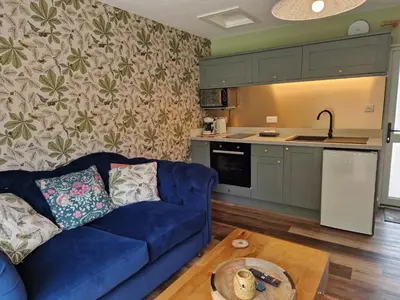 a living room with a blue couch and a kitchen at The Drey by Blake view holidays, a peaceful boutique retreat, 3 miles from Ennerdale- small twin or king bed available in Arlecdon