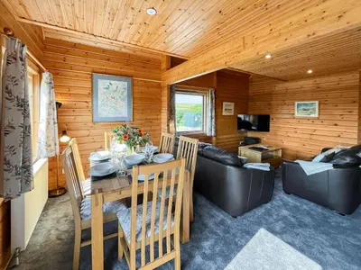 a dining room and living room with a table and a couch at Bengairn in Ringford