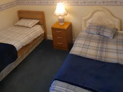 a bedroom with two beds and a lamp on a night stand at Smriti's in Dumfries