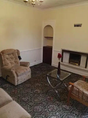 a living room with a couch and a chair and a fireplace at Smriti's in Dumfries