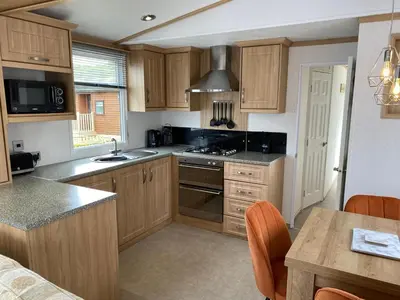 a kitchen with wooden cabinets and a stove top oven at Rosie in Whithorn