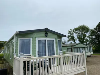 a green tiny house with a white fence at Rosie in Whithorn