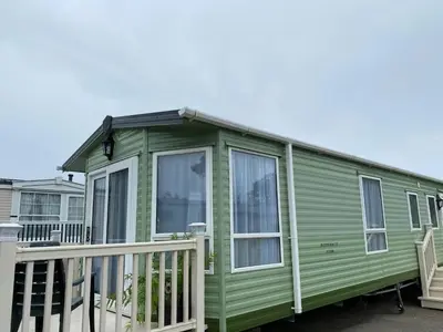 a green tiny house with a porch at Rosie in Whithorn