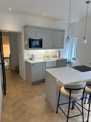 a kitchen with white cabinets and a table and chairs at Luxury High Street Apartment in Moffat