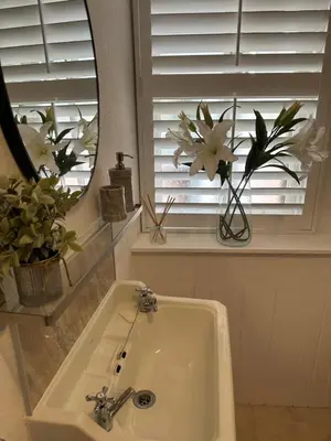 a bathroom with a sink and a mirror and flowers at Luxury High Street Apartment in Moffat