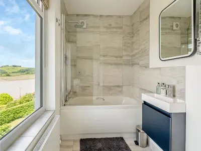 a bathroom with a tub and a sink and a window at Berkeley in Kippford