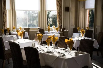 a dining room with tables and chairs with yellow flowers on them at Keswick Country House Hotel in Keswick