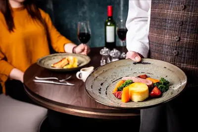 two people holding two plates of food on a table at Skiddaw Hotel in Keswick
