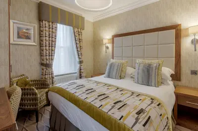 a hotel room with a large bed and a chair at Skiddaw Hotel in Keswick
