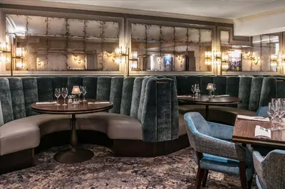 a restaurant with green velvet booths and tables at Skiddaw Hotel in Keswick