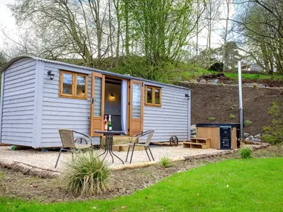 a tiny house with a table and chairs in a yard at Lintmill Lodges - Bluebell Shepherds Hut in Sorn
