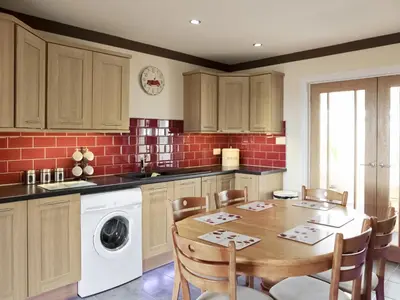 a kitchen with a table and a washing machine at Firth Lodge in Mainsriddle