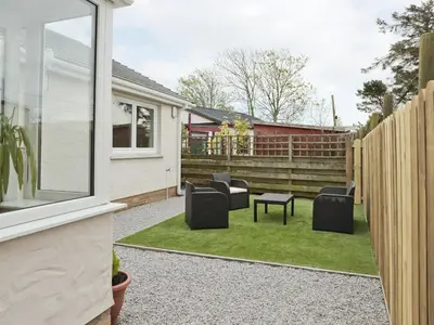 a patio with chairs and a table and a fence at Firth Lodge in Mainsriddle