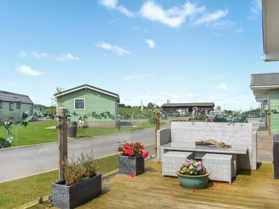 a patio with two benches and flowers on a deck at Meadows Lodge - Uk46825 in Plumbland