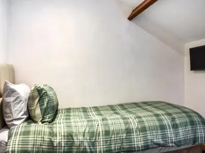 a bed with a green plaid pillow in a room at Uk46833 - Low Hollas Farmhouse in Threlkeld