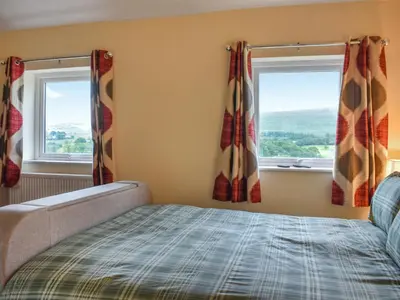 a bedroom with a bed and two windows at Uk46833 - Low Hollas Farmhouse in Threlkeld