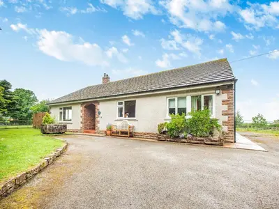 a small white house with a driveway at Stackgarth in Gilcrux