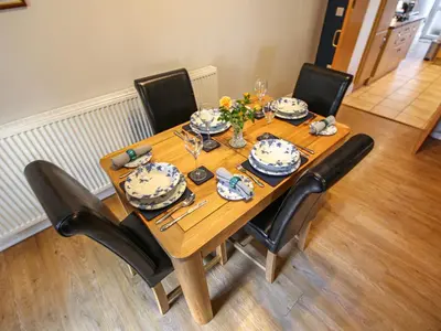 a wooden table with chairs and plates and dishes on it at The Bothy in Ivegill