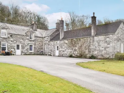 an old stone building with a road in front of it at Park Cottage in Gatehouse of Fleet