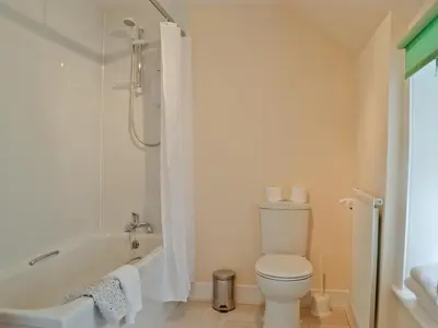 a bathroom with a tub and a toilet and a sink at Park Cottage in Gatehouse of Fleet