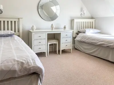 a bedroom with two beds and a desk with a mirror at Balnowlart Lodge in Ballantrae