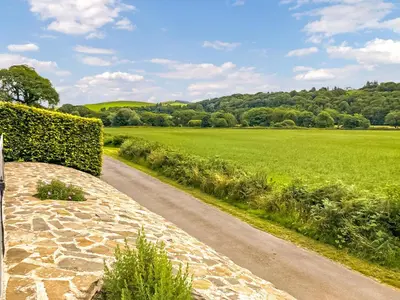 a road leading to a green field with a hedge at Balnowlart Lodge in Ballantrae