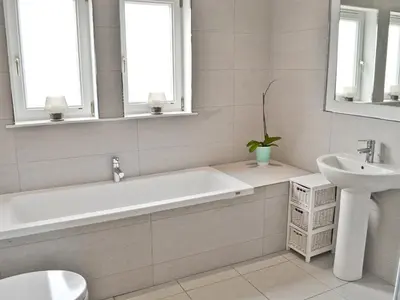 a white bathroom with a tub and a sink at Bengali in Ringford
