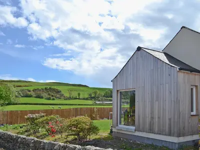 a small wooden house with a fence and a field at Bengali in Ringford