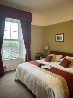 a bedroom with a large bed and a window at Daviot Guest House in Ayr