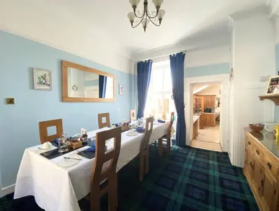 a dining room with blue walls and a table with chairs at Daviot Guest House in Ayr