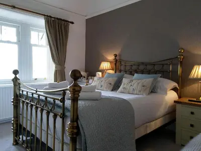 a bedroom with a large bed with white sheets and pillows at Lakeside Country Guest House in Bassenthwaite Lake