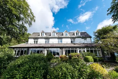 an exterior view of a large white house with windows at Borrowdale Gates Hotel in Keswick