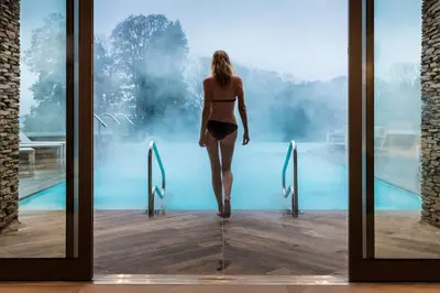 a woman in a bikini walking into a swimming pool at Lodore Falls Hotel & Spa in Keswick