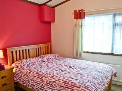 a bedroom with a bed and a red wall at Catbank in Bridekirk
