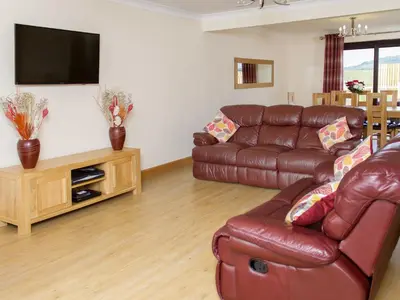 a living room with a leather couch and a flat screen tv at Seascape in Mainsriddle