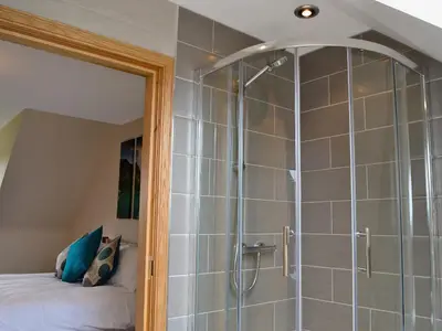 a shower with a glass door in a bedroom at Seascape in Mainsriddle