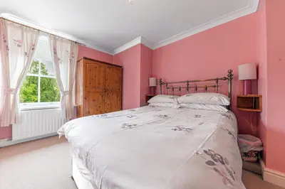 a bedroom with a bed with pink walls and a window at Stickle Tarn in Keswick