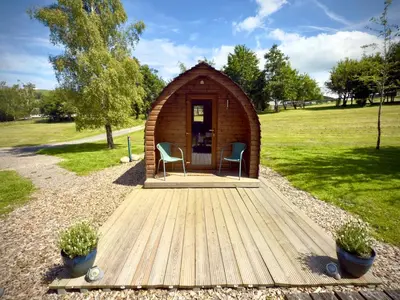 a small wooden cabin with two chairs on a wooden deck at Howbeck Lodge in Hesket Newmarket