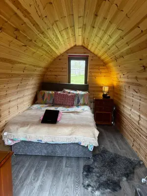 a bedroom with a bed in a wooden cabin at Howbeck Lodge in Hesket Newmarket