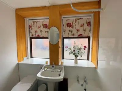 a bathroom with a sink and two windows with flowers at Charming Cosy Traditional Scottish Cottage - Pass the Keys in Castle Douglas