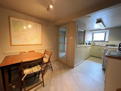 a dining room with a table and a kitchen at Charming Cosy Traditional Scottish Cottage - Pass the Keys in Castle Douglas