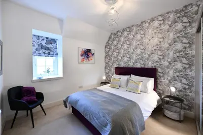 a bedroom with a king sized bed and a chair at 20 The Courtyard, Ballochmyle House in Mauchline