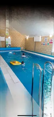 two people swimming in a pool with a yellow surfboard at Turnberry Holiday Park in Turnberry