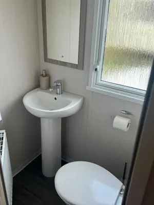 a bathroom with a white sink and a toilet at Robinson retreats beautiful caravan with sea views pet friendly in Mainsriddle