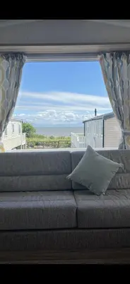 a couch with a view of the ocean through a window at Robinson retreats beautiful caravan with sea views pet friendly in Mainsriddle