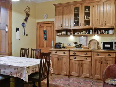 a kitchen with wooden cabinets and a dining table at Ewes Schoolhouse in Bentpath