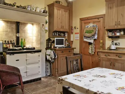 a kitchen with wooden cabinets and a table in it at Ewes Schoolhouse in Bentpath