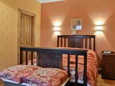a bedroom with a bed with a wooden frame and lights at Ewes Schoolhouse in Bentpath
