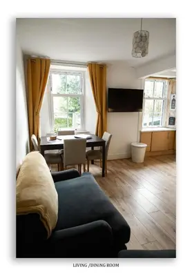 a living room with a couch and a dining room table at Clarefoot Cottage in Moffat